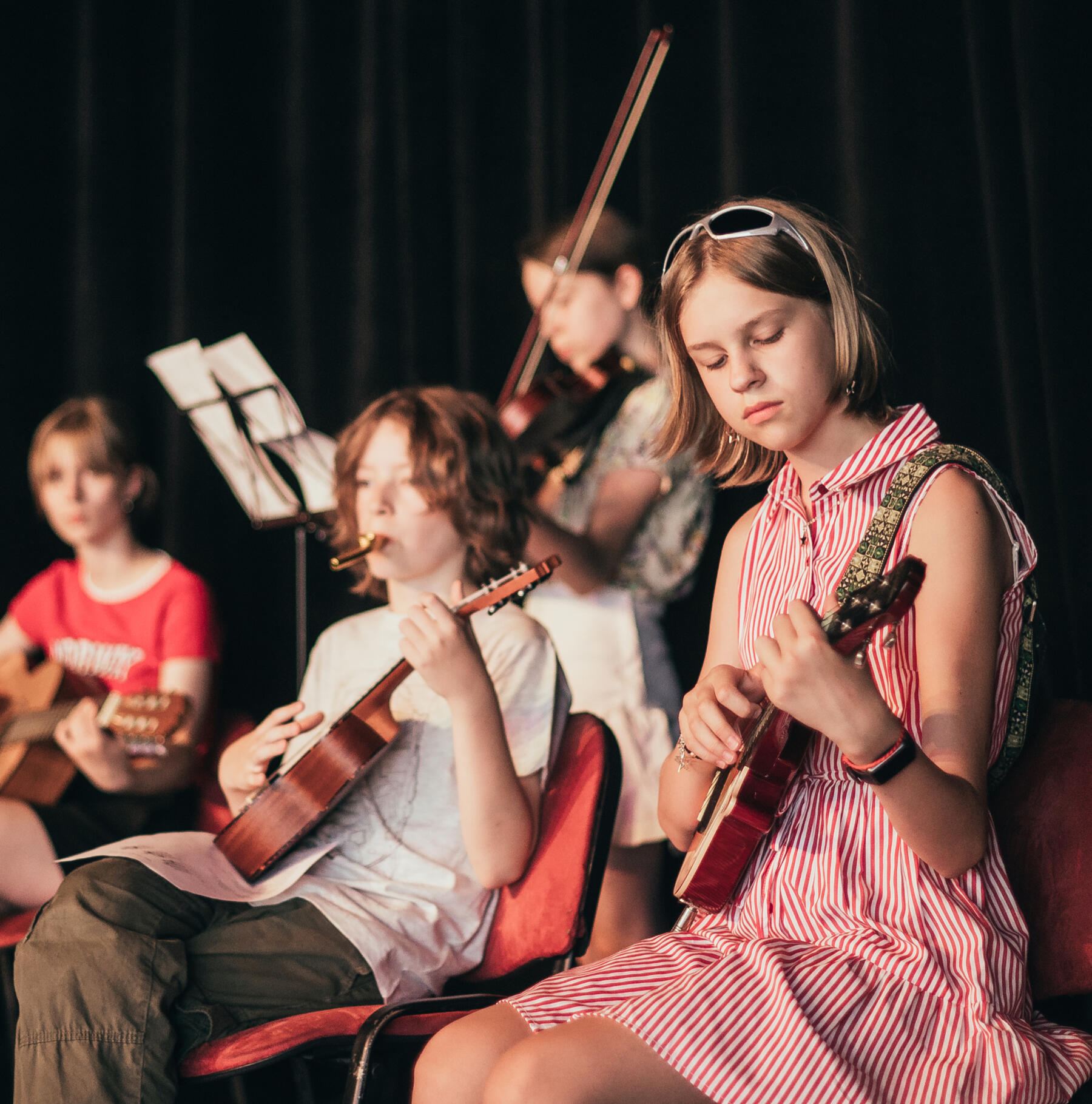 young student playing the ukelele for an audience
